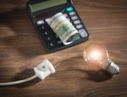A bulb, an electrical plug, a calculator, money, all in a single frame